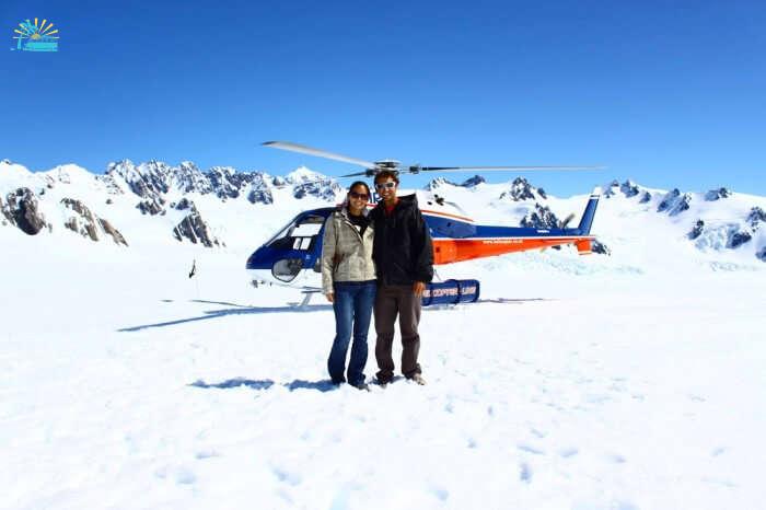A couple poses with the helicopter used on the heli-hike at Fox Glacier