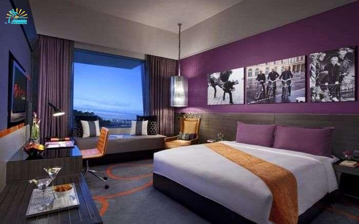 A king size bed and a huge glass window in a hotel room