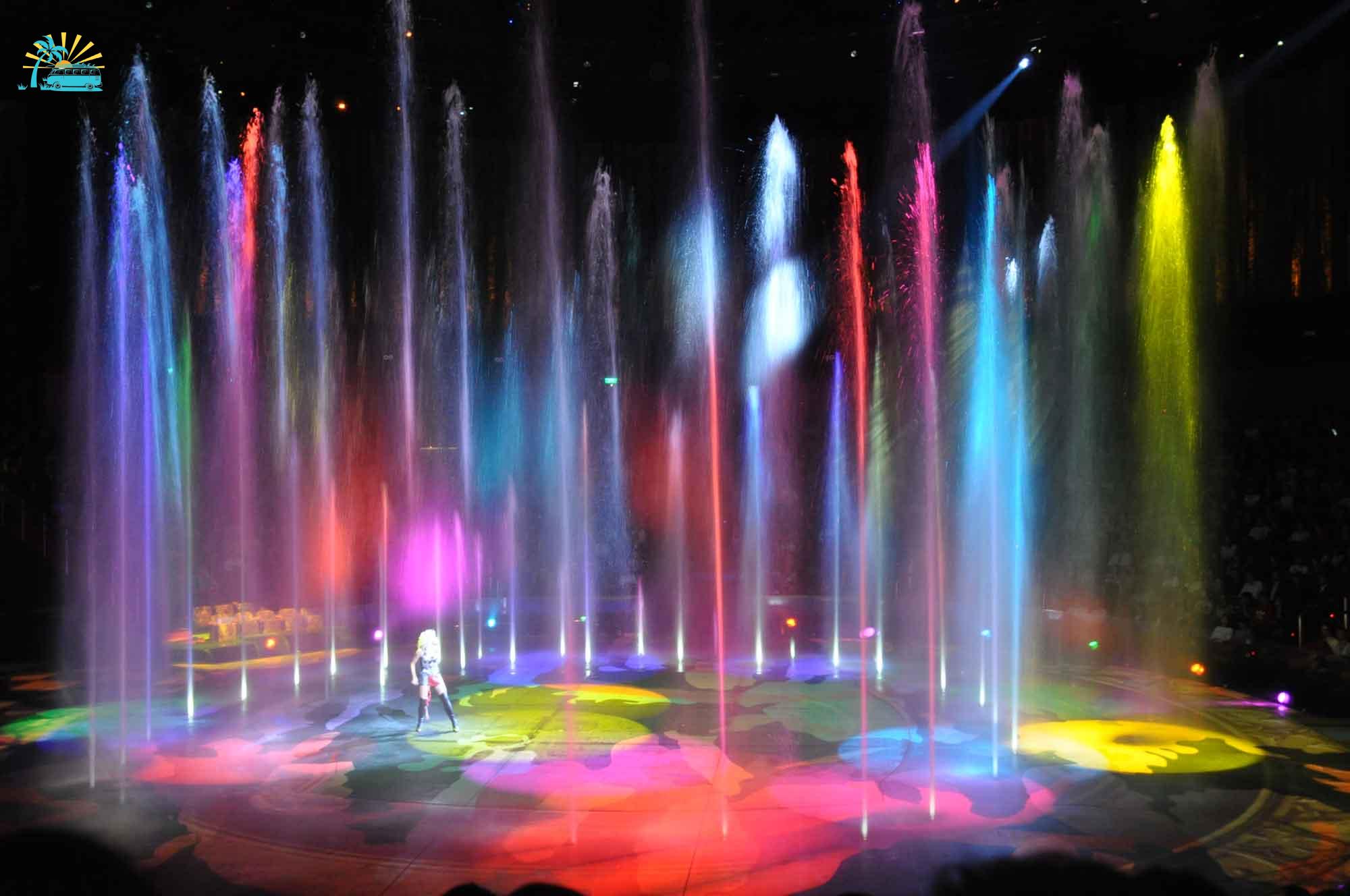 A lady performing solo in the middle of colorful water fountains