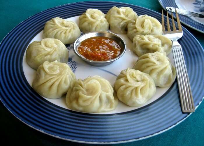 A plate full of momos and red chutney served at various food stalls in Kasauli
