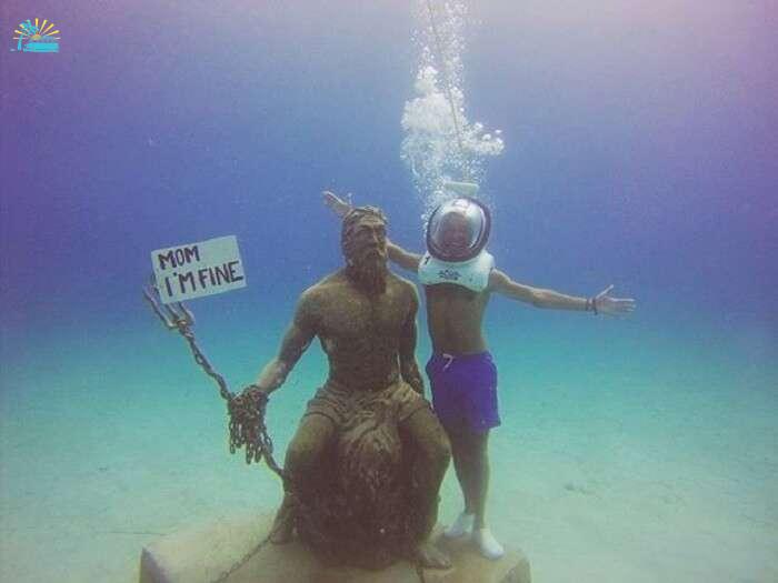 Jonathan Quiñonez underwater with a Posiedon statue in Columbia