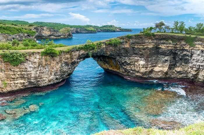 Stone arch over the sea at the rocky coastline on Nusa Penida island near Bali in Indonesia