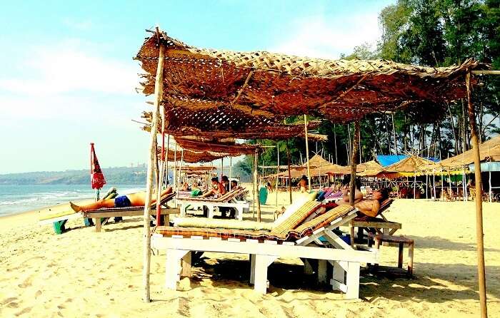 Tourists relax at the recliners and boat shacks at Querim Beach