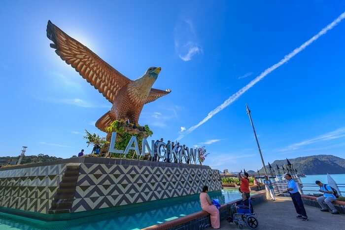 Tourists sit and relax at the 12 meter-tall Eagle Square in Langkawi