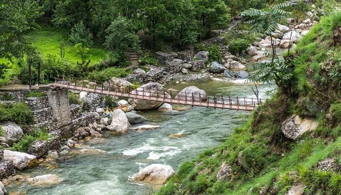 Wooden pedestrian hanging bridge over tirthan river in Tirthan Valley