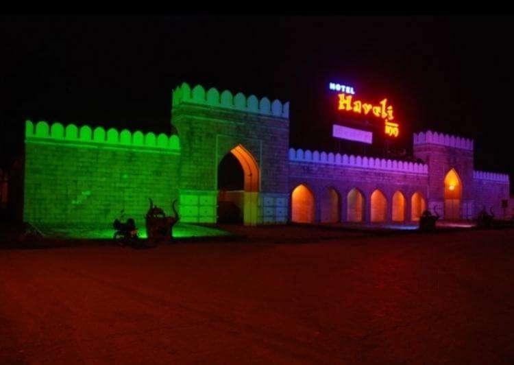a haveli style entrance of a resort painted with colourful lights
