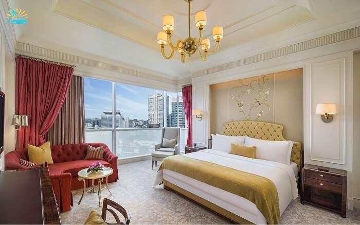 hotel room with chandelier and king size luxurious bed and a glass window