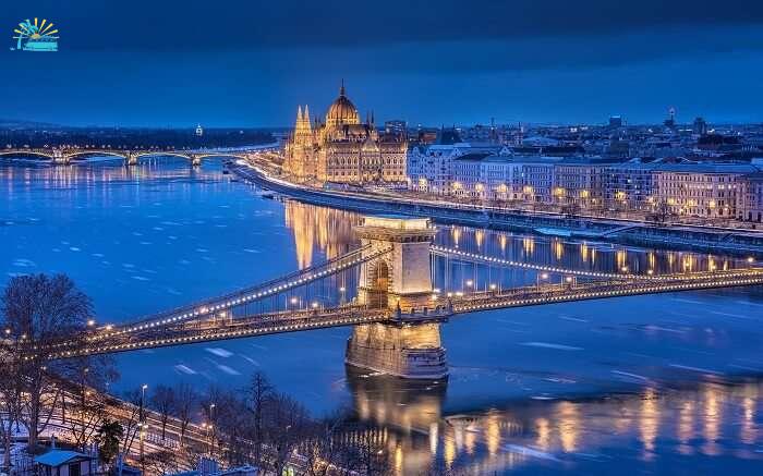 well lit Budapest parliament and bridge at night